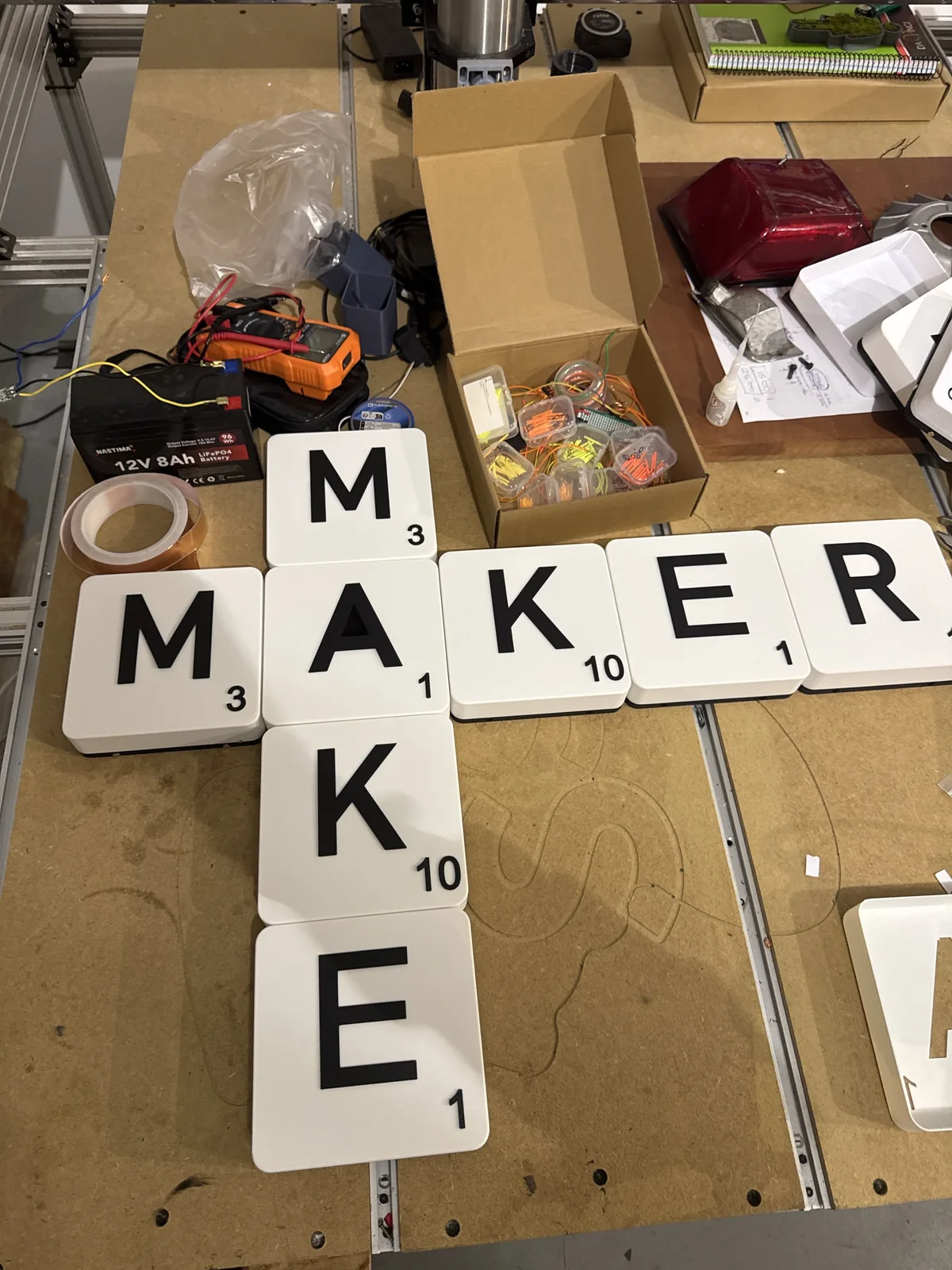 Conjunto real de fichas de letras y números formando una composición cruzada en la mesa del taller